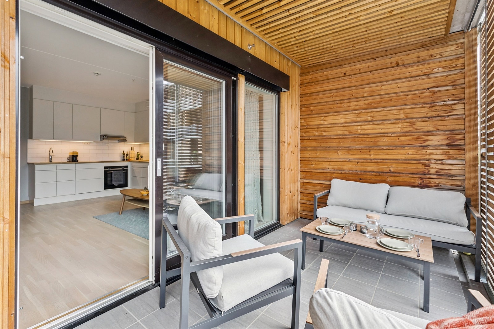 Balkongen har flislagt gulv og trepanel, som skaper en lun og privat uteplass. Galleribilde