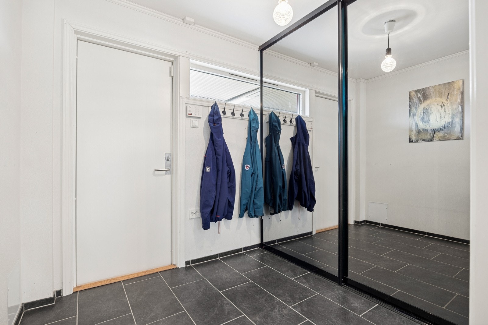 Entréen gir et godt førsteinntrykk med lysmalte veggflater, flislagt gulv med behagelig gulvvarme og gode oppbevaringsmuligheter i skyvedørsgarderobe. Galleribilde