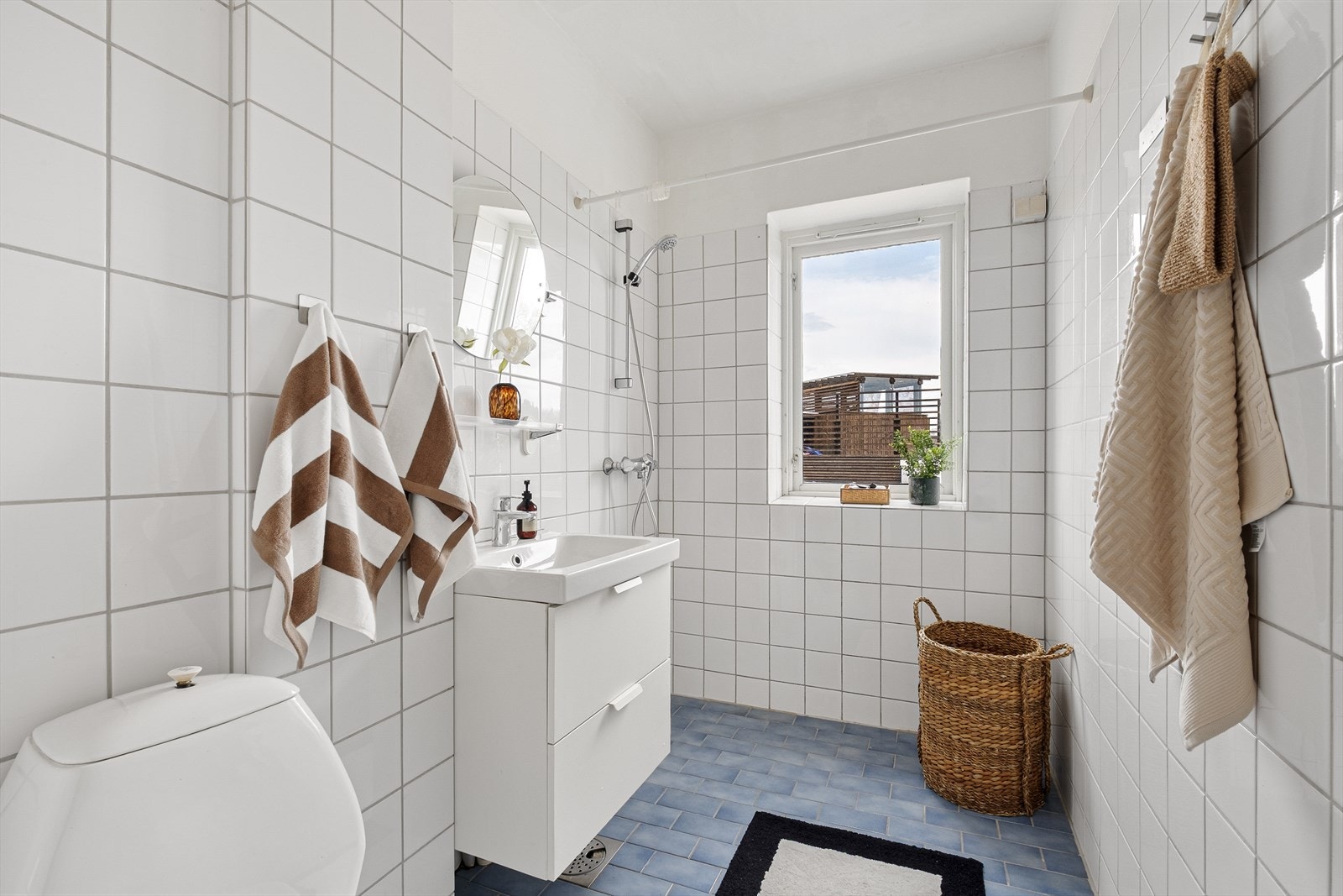 Flislagt baderom med varmekabler, avtrekk, speil, lampe, servant med innredning, dusjhjørne, toalett. Galleribilde