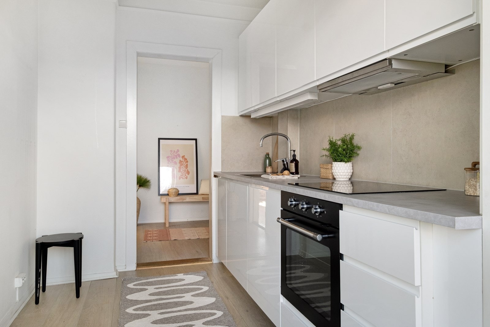 Pen kjøkkeninnredning med hvite glatte fronter. Integrert stekeovn og oppvaskmaskin. Avsatt plass til kjøleskap. Galleribilde