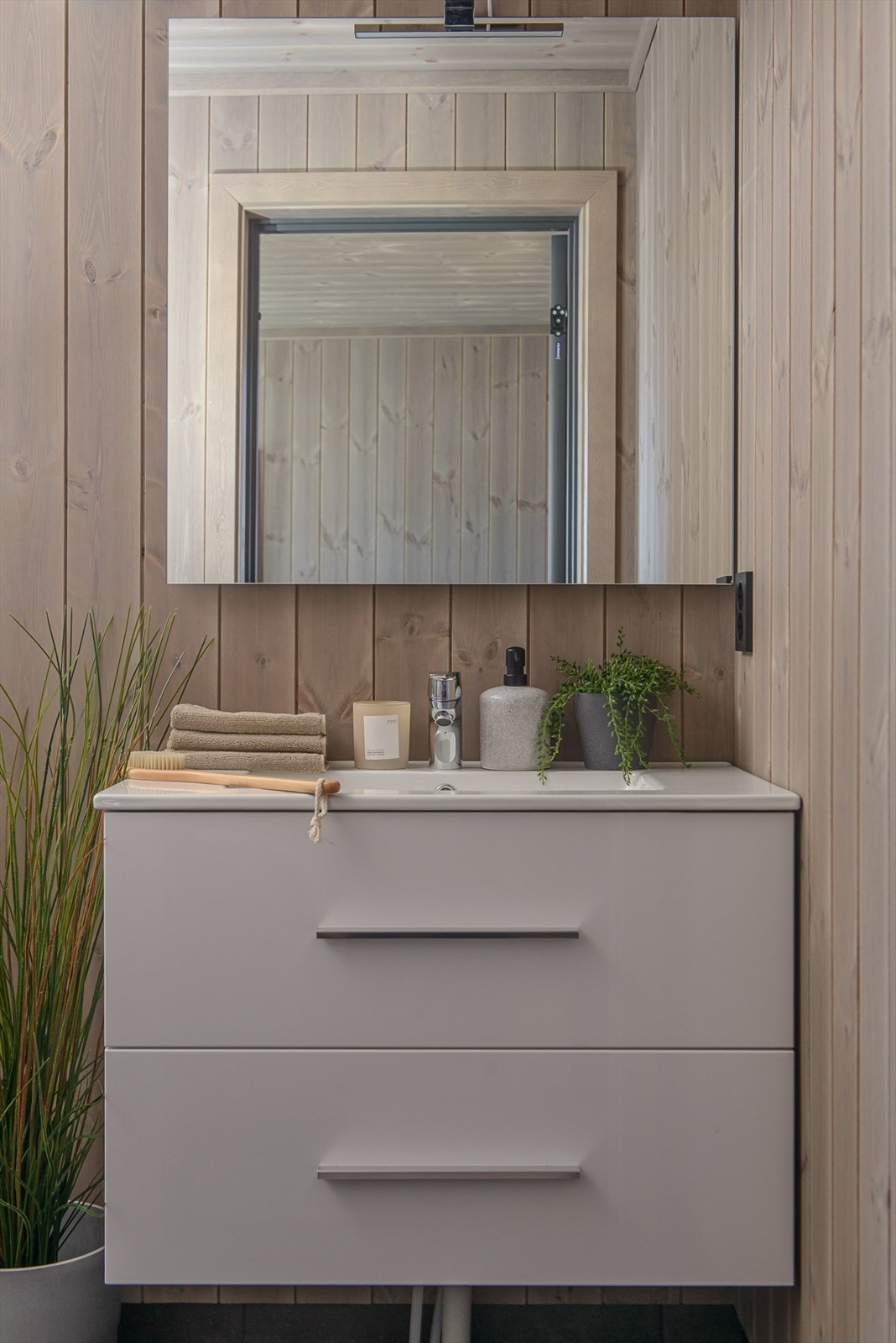 Moderne baderomsinnredning med hvite høyglans skuffefronter og heldekkende servanttopp. Galleribilde