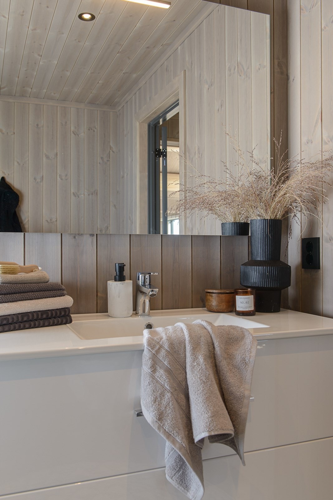 Moderne baderomsinnredning med hvite høyglans skuffefronter og heldekkende servanttopp. Galleribilde