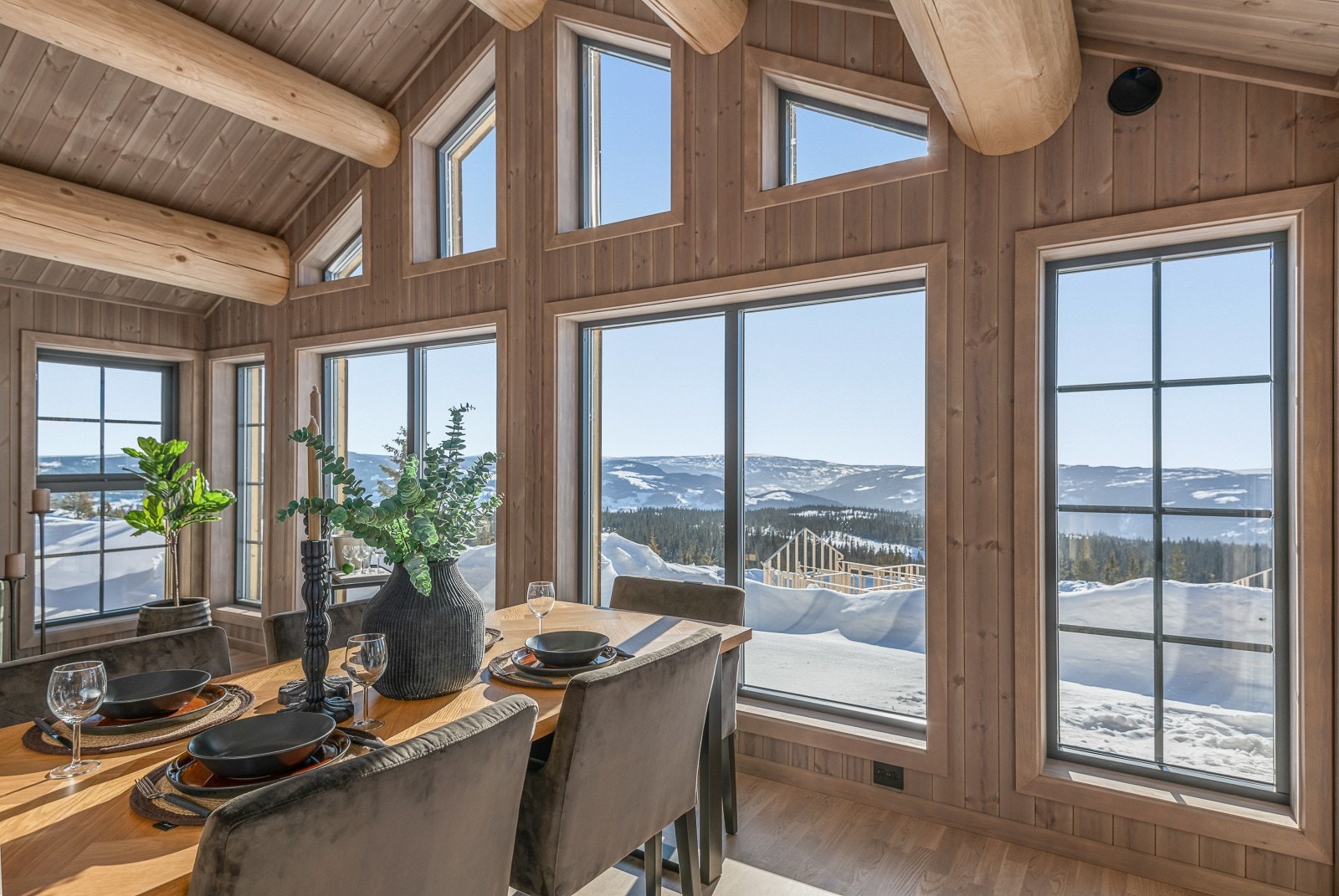 Store vinduer åpner for den storslagne utsikten, og de store, grove takåsene bidrar til den rette hyttefølelsen. Galleribilde