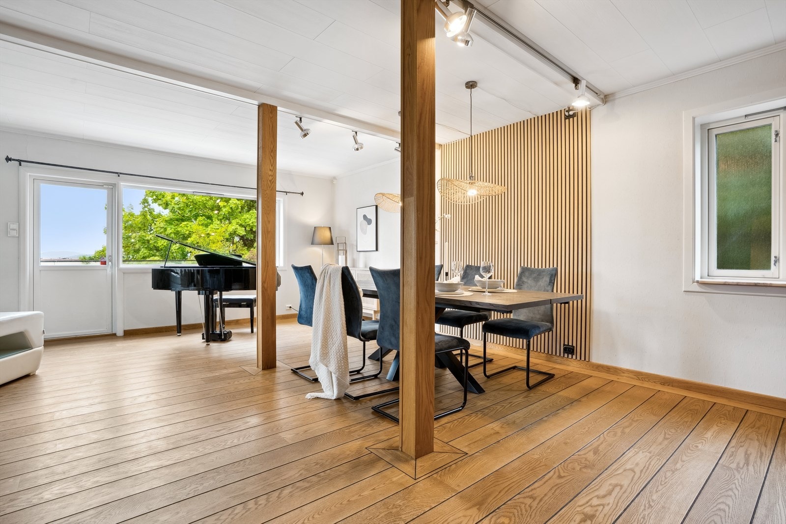 Spisestuen er adskilt med en moderne spilevegg fra gulv til tak og innrammet av bjelker, noe som skaper et rom i rommet. Galleribilde