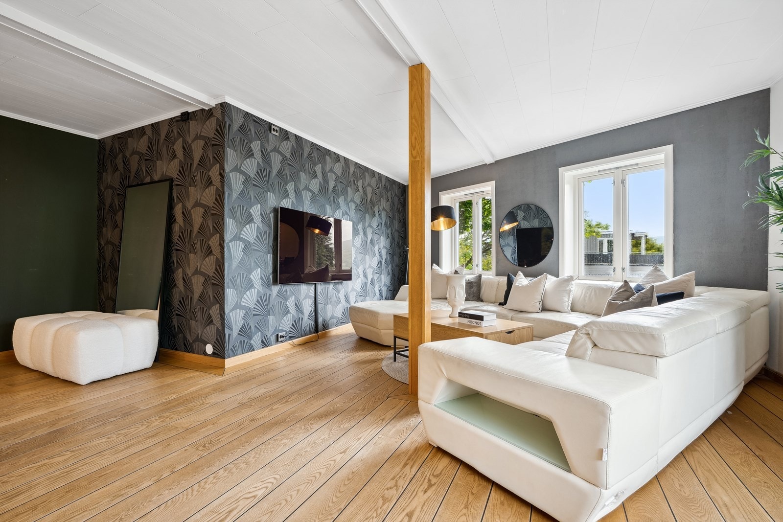 Stuen kan enkelt deles inn i flere soner og har en fondvegg i en dus gråfarge, samt en vegg med lekker mønstret tapet som skiller seg ut fra de andre veggene. Galleribilde