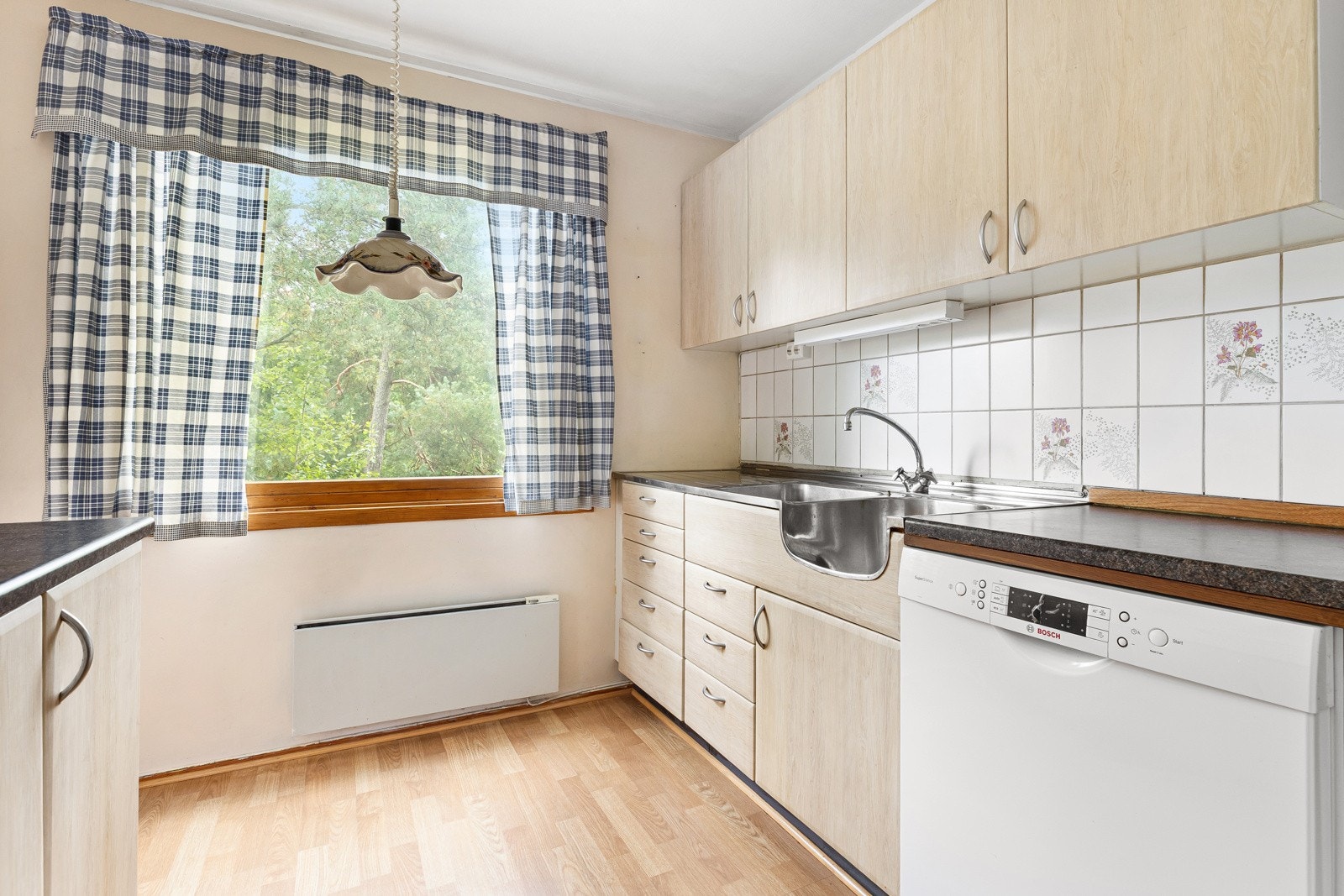 Kjøkkeninnredning fra ukjent årstall med glatte fronter. Benkeplater av laminat. Oppvaskkum av rustfritt stål med to-greps armatur. Fliser på vegg over oppvaskbenk. Galleribilde