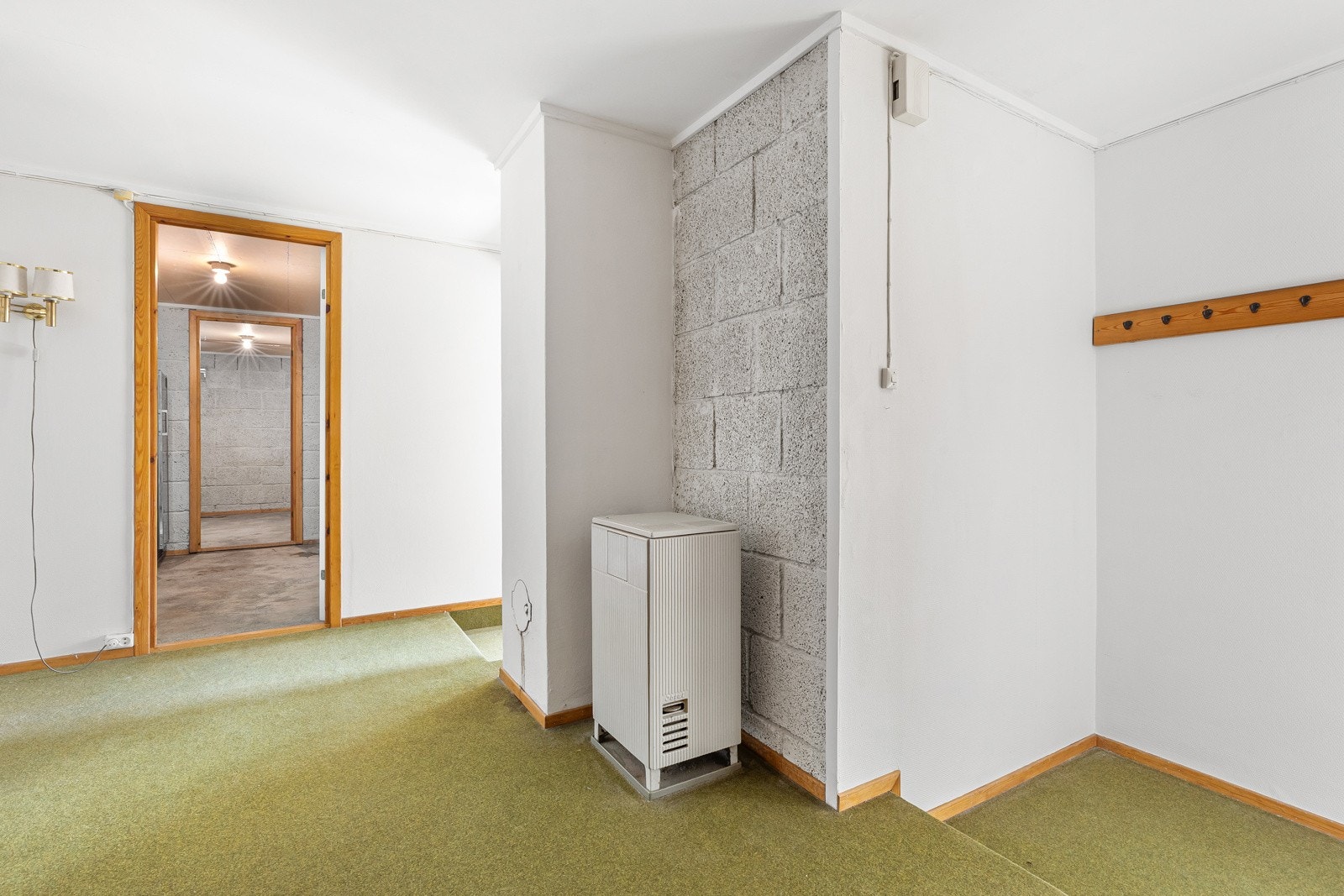 Mellomgang i underetasje belagt med vegg-til-vegg tepper. Veggflater belagt med malte strietapeter, trepaneler og malte murkonstruksjoner. Galleribilde