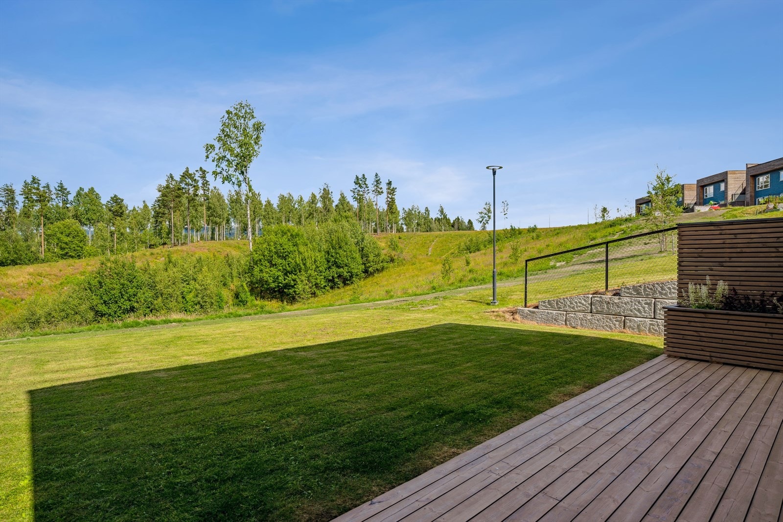 På baksiden av boligen kan du sitte skjermet på den 24m2 store terrassen. Sett føttene på gresset og nyt friske grøntarealer. Galleribilde