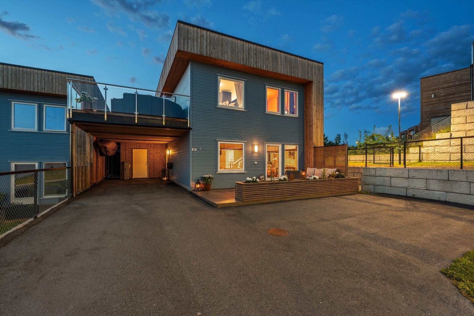 Stram fasade og gårdsplass med asfalt som gir et rent og strøkent inntrykk. Carporten på 32m2. Bakerst i carporten er det sportsbod på 5m2. Galleribilde