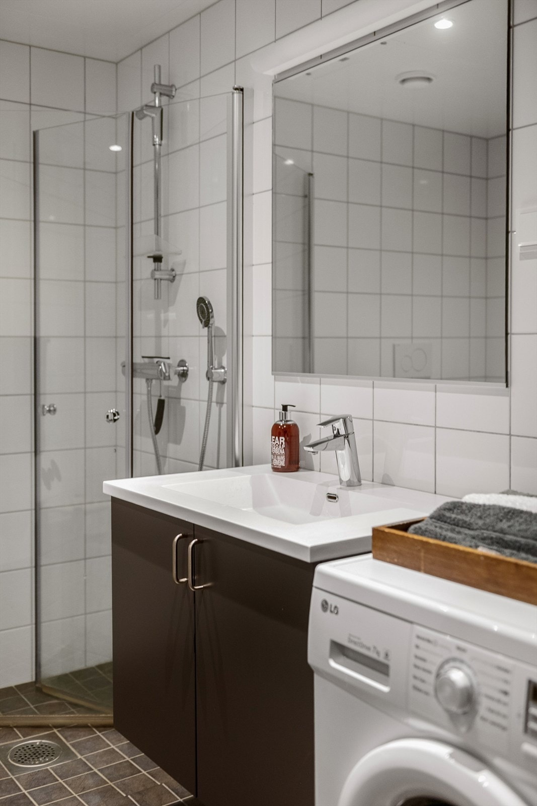 Servant med underskap, speil med tilhørende belysning, vegghengt wc og innfellbare dusjvegger. Galleribilde