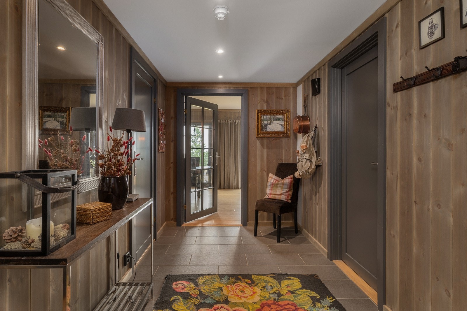 Romslig gang med flislagt gulv, panelte vegger og himling med downlights. Varme i gulvet gir en ekstra behagelig komfort. Galleribilde