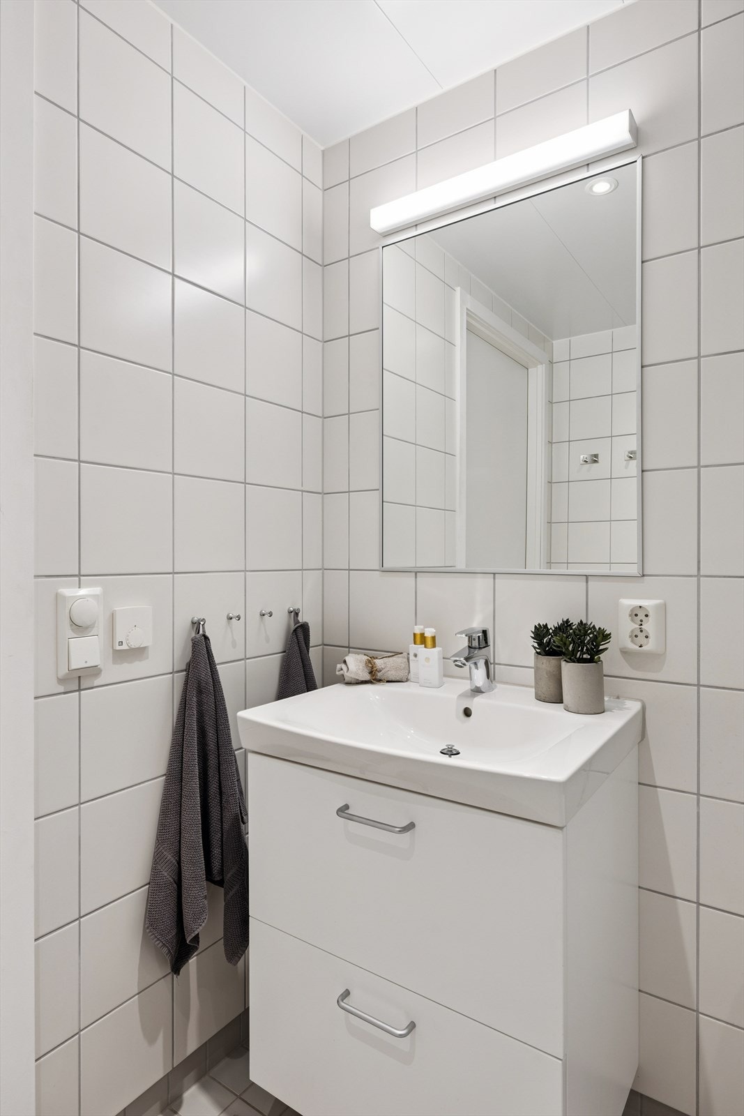 Innredningen består av servant med underskap, speil med belysning og et vegghengt toalett. Galleribilde