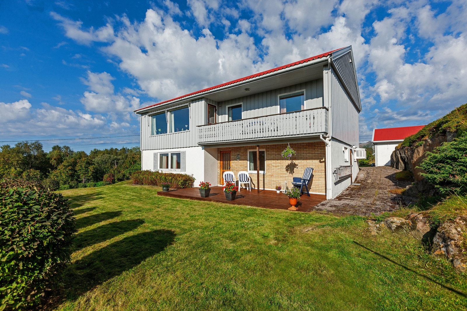 Eiendommen er pent opparbeidet med prydbusker, velholdt plen og annen beplantning Galleribilde