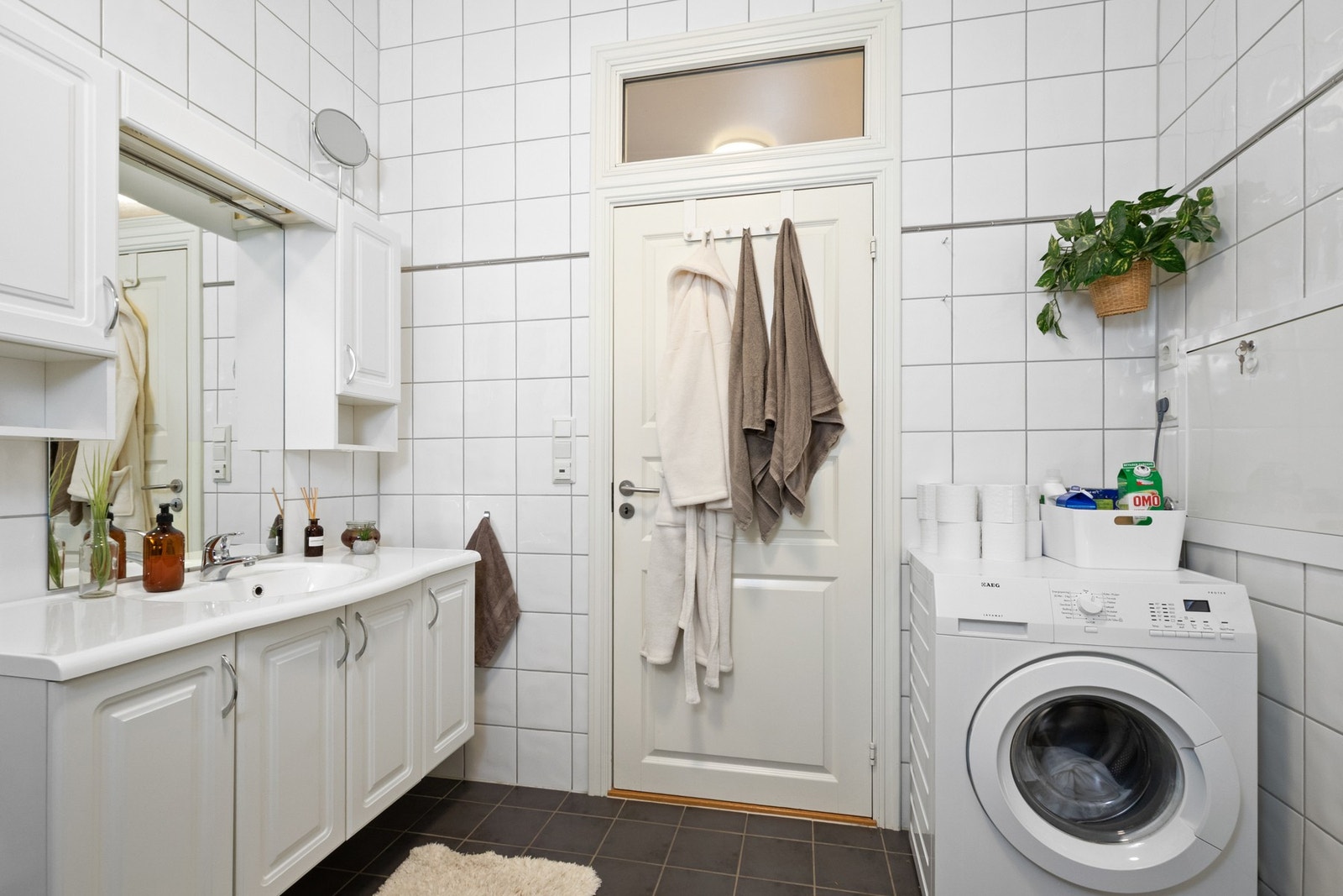 Romslig baderomsinnredning med heldekkende servant og speil med belysning. Galleribilde