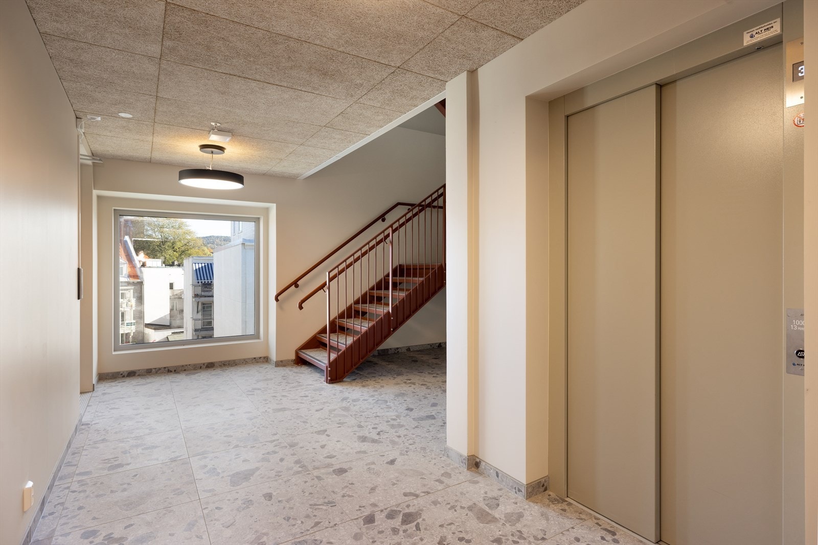 Lys og moderne felles trappegang med flislagt gulv og store vinduer. Heis tilgjengelig for enkel adkomst. Galleribilde