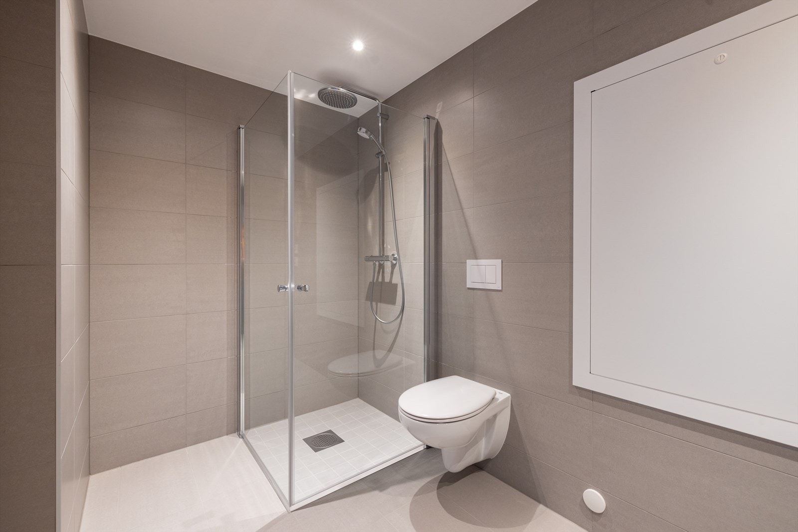 Pent, flislagt bad med varmekabler i gulv og veggmontert toalett. Nedsenket dusjhjørne med dusjvegger. Innfelte LED downlights, med dimmer. Galleribilde
