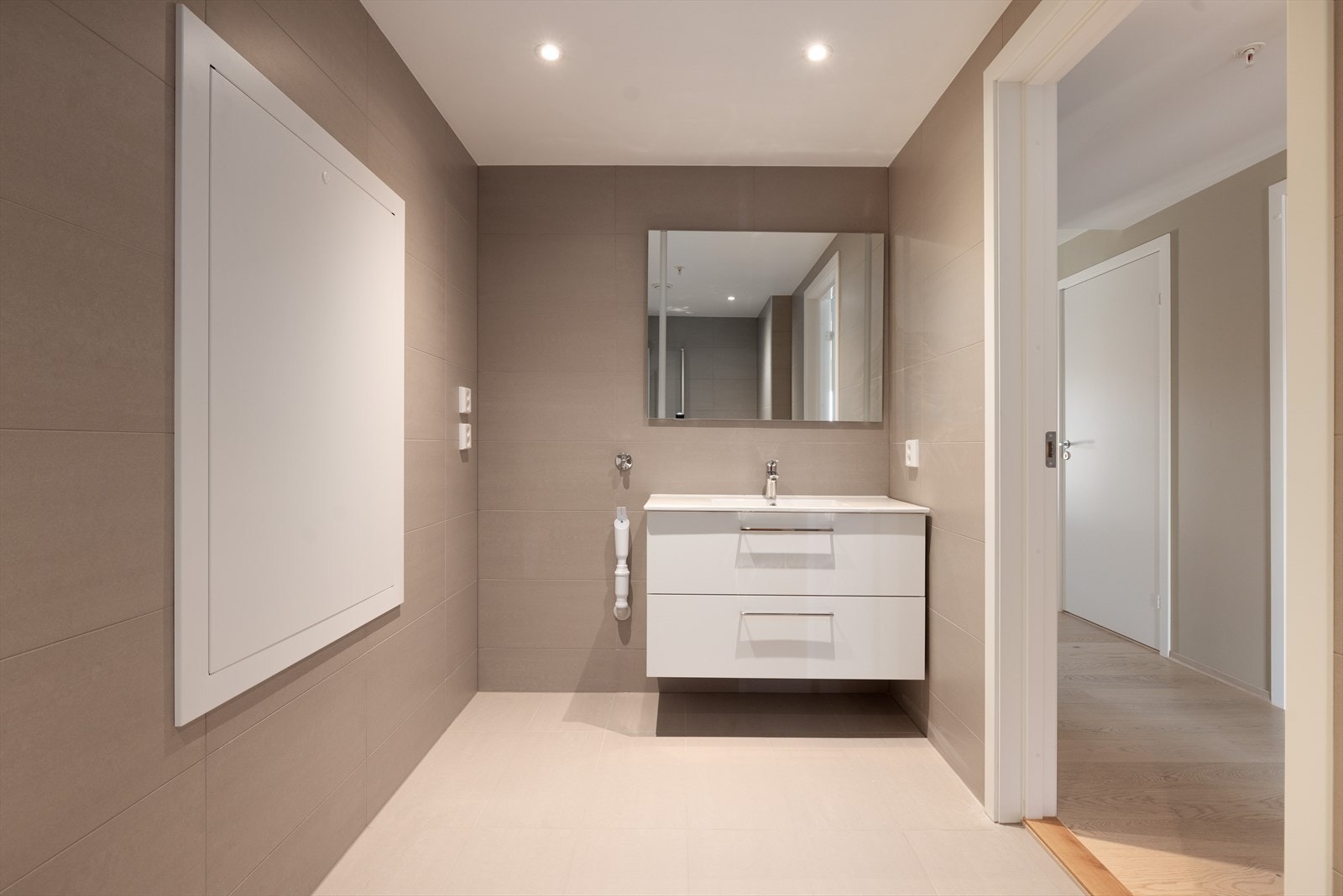 Pen servantinnredning med to skuffer og helstøpt servant, samt speil med integrert LED belysning. Badet har for øvrig opplegg for vaskemaskin. Galleribilde