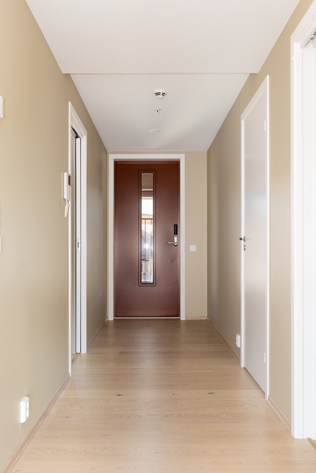 Romslig og fin entré/gang med vannbåren gulvvarme og praktisk porttelefon med video. Fin plass til oppbevaringsmøblement for sko- og yttertøy. Galleribilde