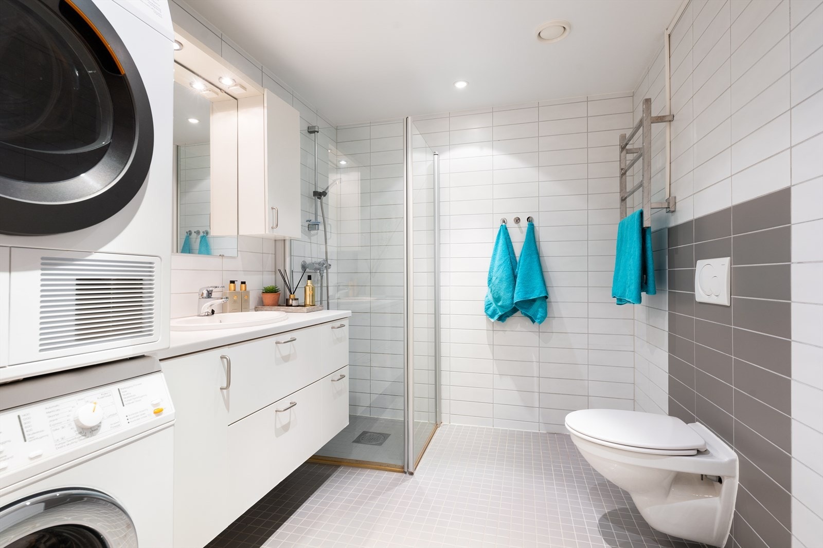 Leiligheten har et lyst flislagt bad med varme i gulv og downlights i himling - Badet har baderomsinnredning bestående av benkeskap, servant og veggskap med glatte fronter Galleribilde