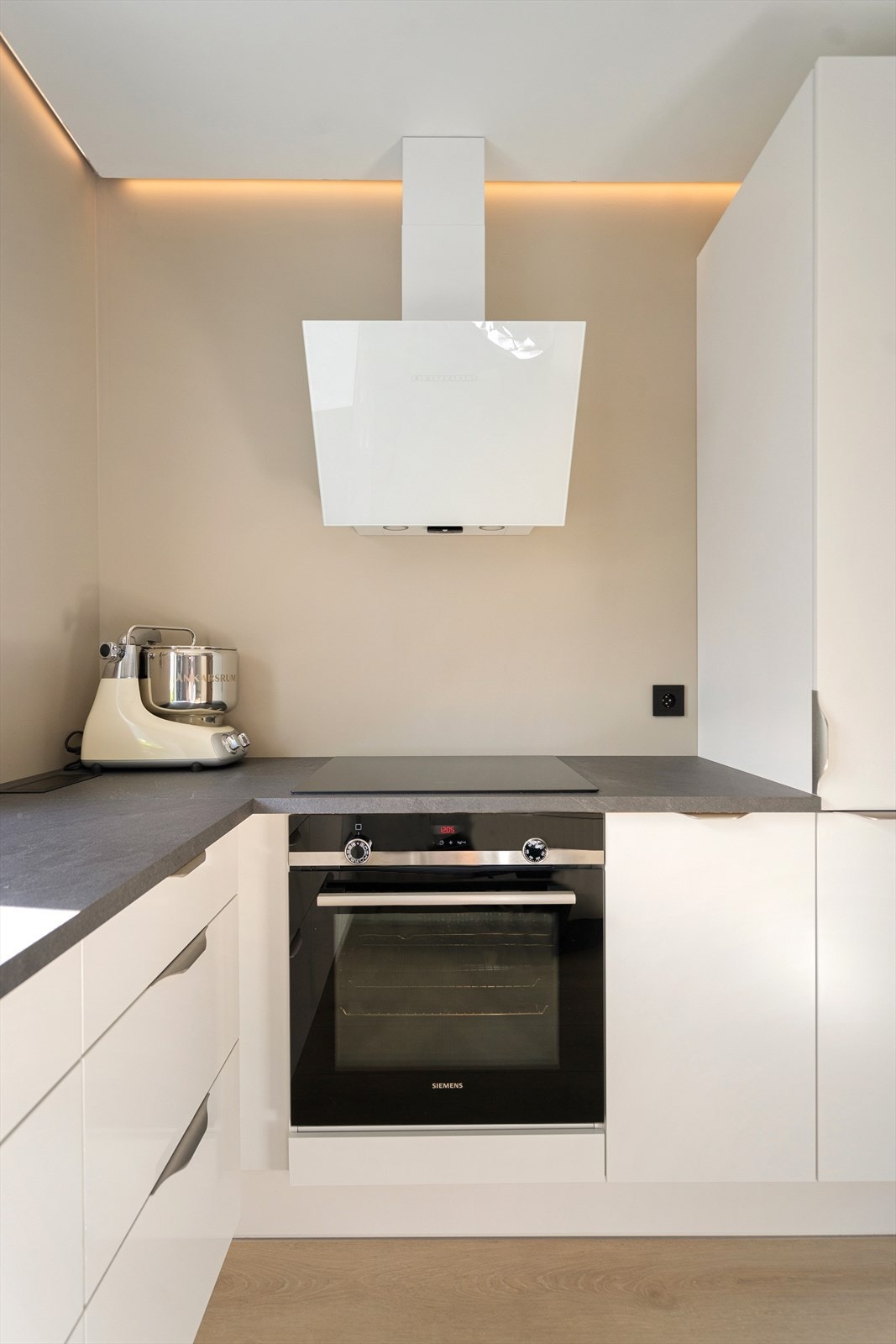 Kjøkkenet er utstyrt med moderne hvitevarer og ventilator i stilrent design Galleribilde