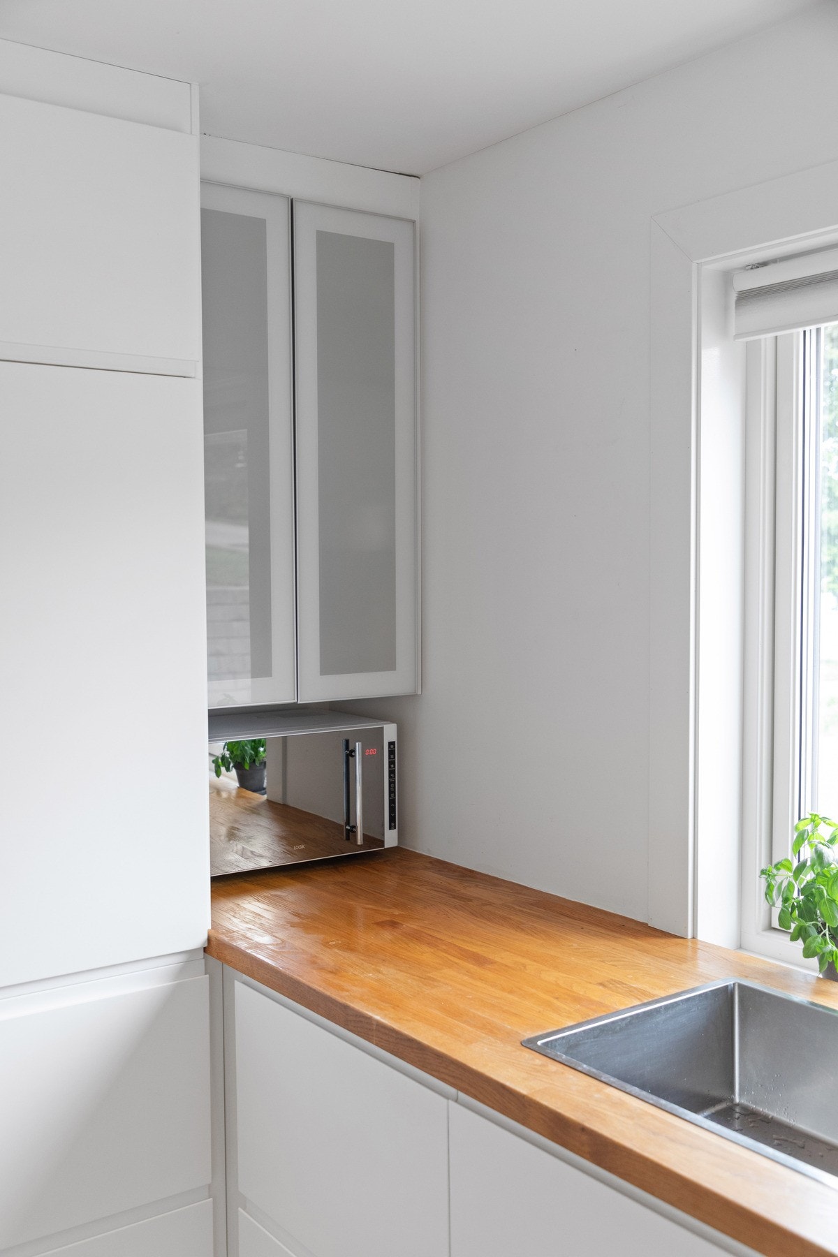 Kjøkkenet har rene linjer, hvite fronter og vitrineskap som gir et stilrent uttrykk. Galleribilde