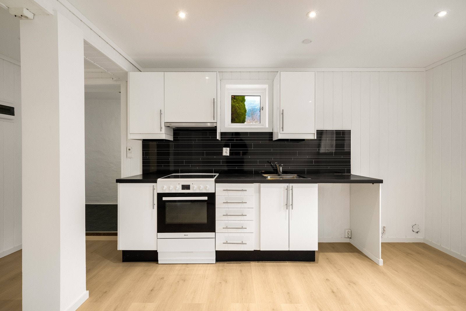 Pent Ikea kjøkkeninnredning med hvite glatte fronter og laminert benkeplate og planlimt kjøkkenbeslag. Galleribilde