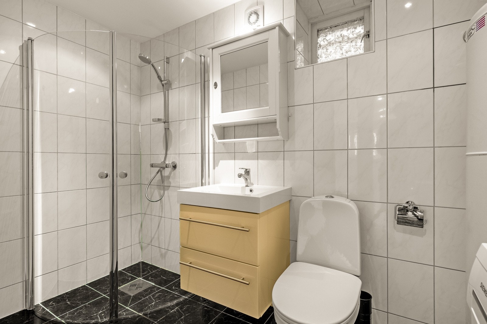 Badet er av god størrelse med innredet dusjhjørne, heldekkende servant og toalett. Galleribilde