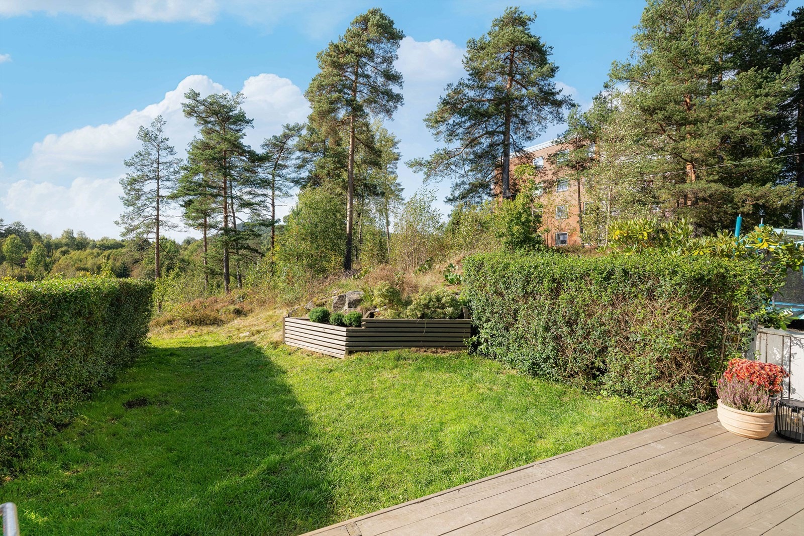 Det er levegg og hekk mot naboene, og ytterst i hagen er det opparbeidet stor, flott blomsterkasse. Galleribilde