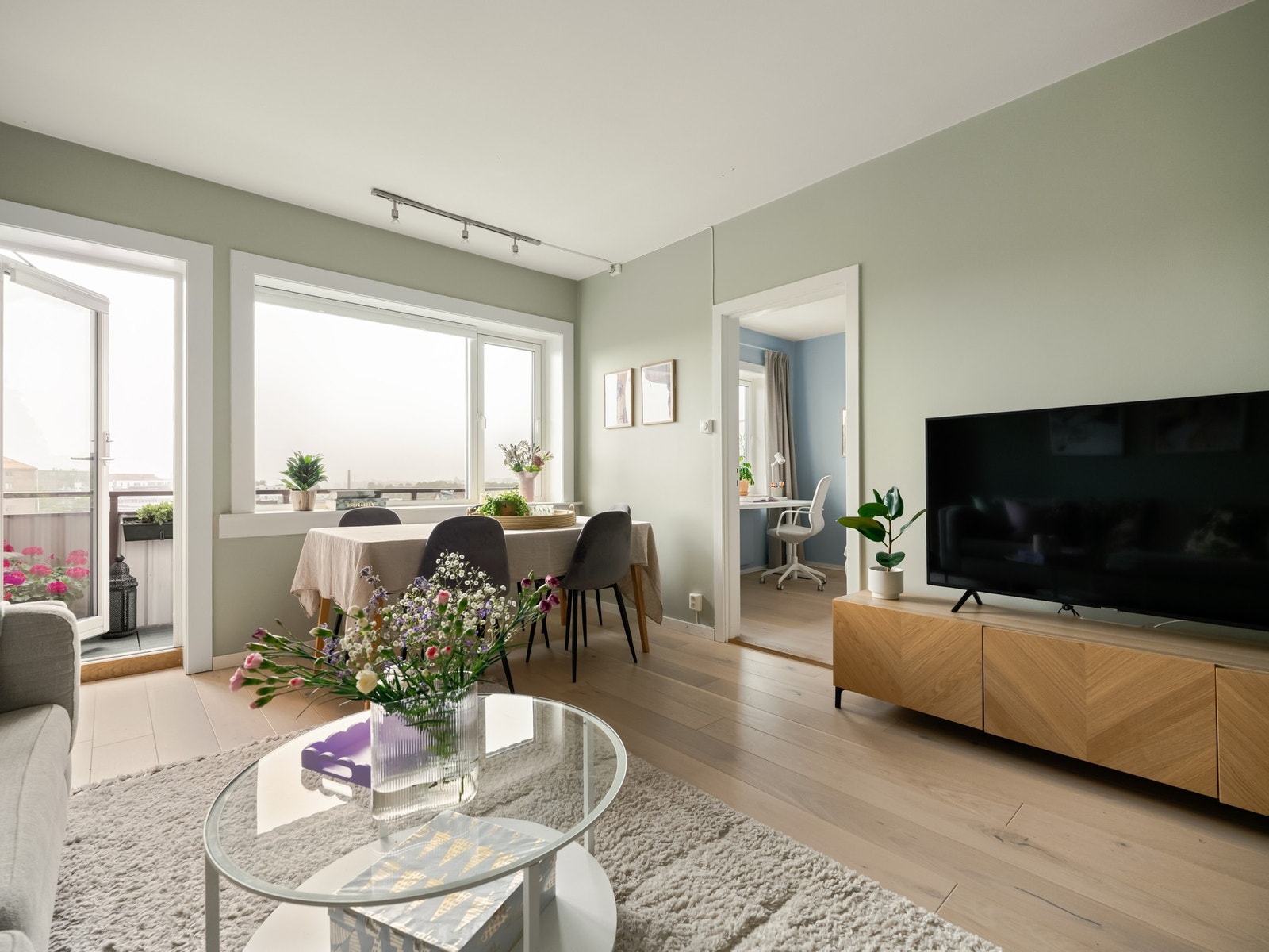 Det er plass til både sofagruppe og spisebord, i tillegg til at vi finner utgangen til boligens balkong herfra. Galleribilde