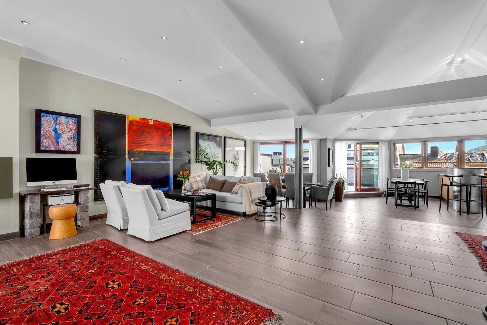 Lys og åpen stue med gjennomgående takhøyde, store vindusflater og flere soner for møblering. Galleribilde