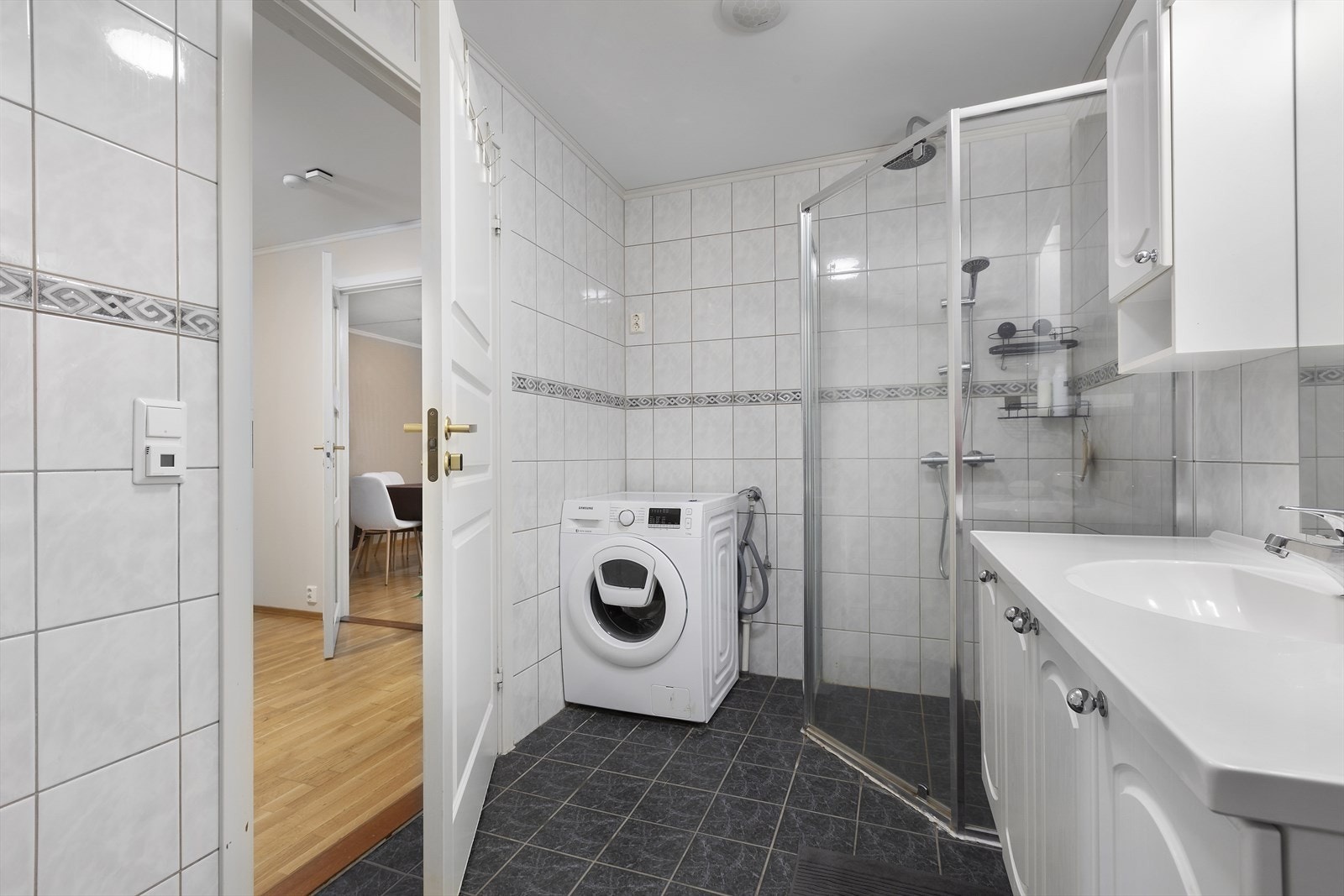 Bad utstyrt med servant og servantinnredning, toalett, dusjhjørne og opplegg for vaskemaskin. Galleribilde