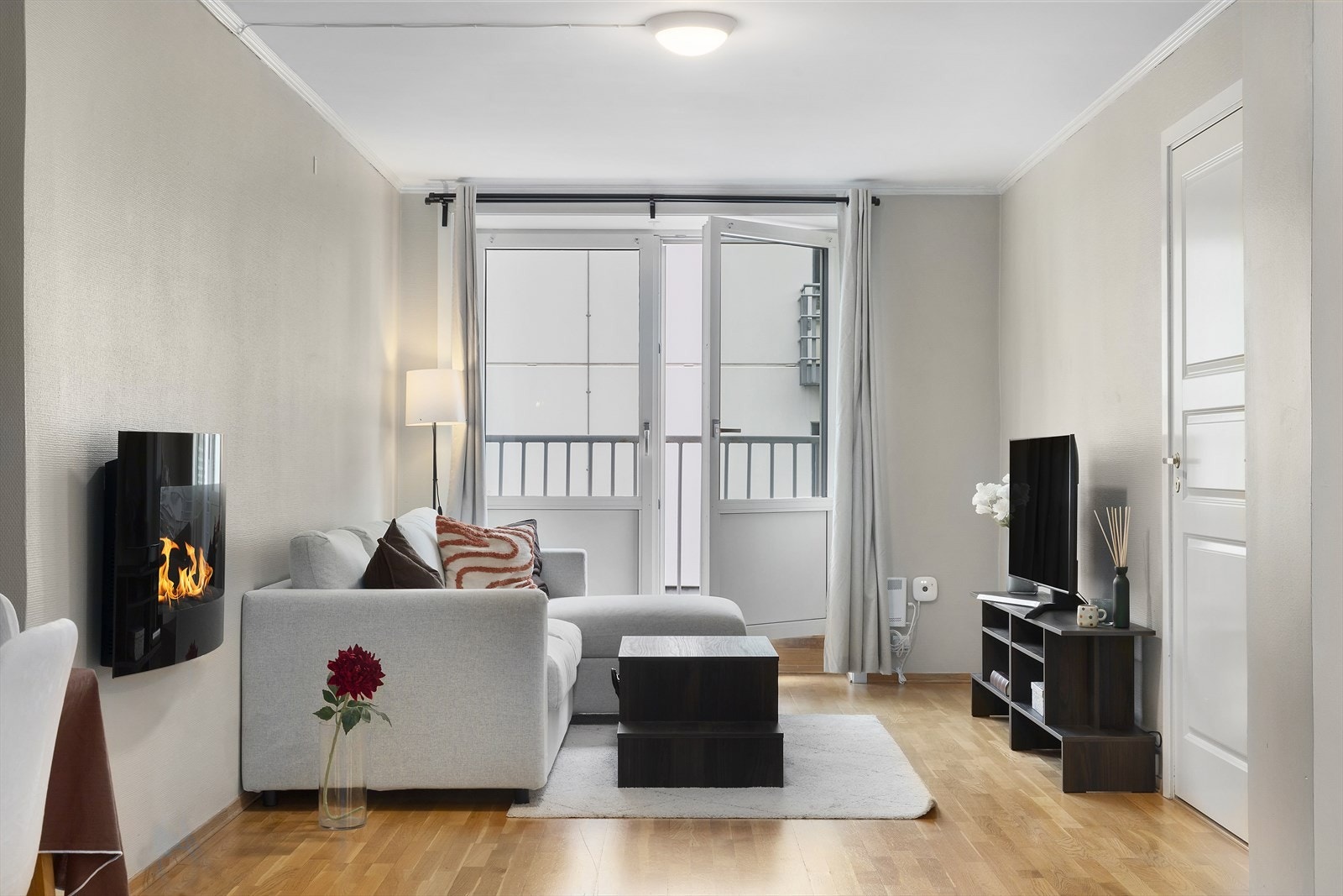 Romslig stue med elektrisk peis, stilrent interiør og direkte utgang til balkong. Galleribilde