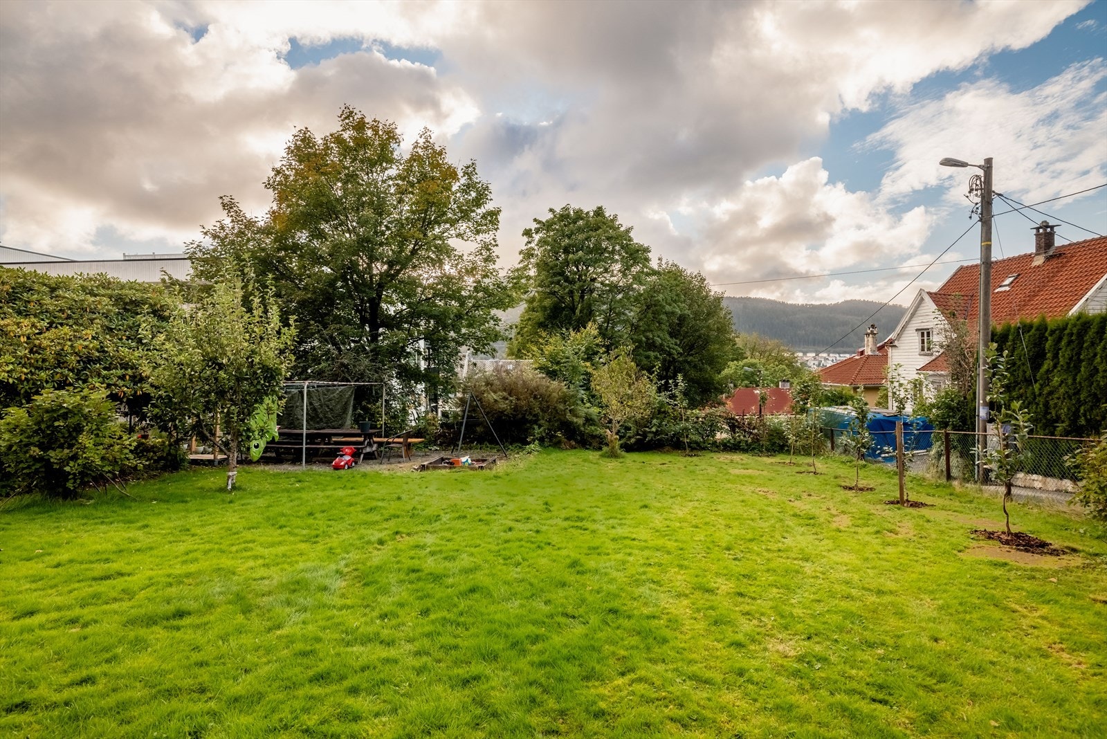 Tomten er felles for sameiet, opparbeidet med grøntarealer, murer/bed, sandkasse, epletre og div prydbusker/beplantning. Galleribilde