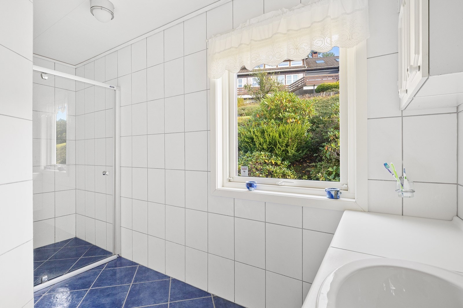 Badet er innredet med innredning med nedfelt servant, dusjhjørne med glassvegger og toalett. Badet har en elektrisk vifte i taket og luftespalte i dør. Galleribilde