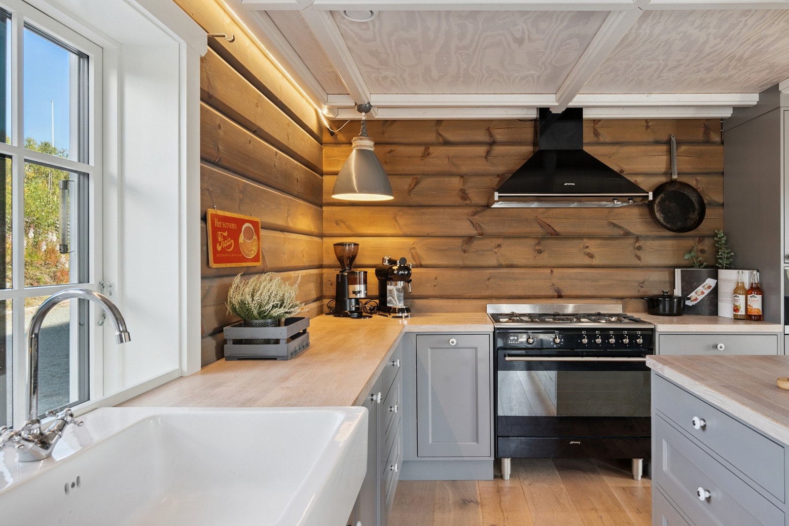 Klassiske fronter i dempede fargetoner kombineres med heltre benkeplater og detaljer i sort og messing for et elegant uttrykk Galleribilde