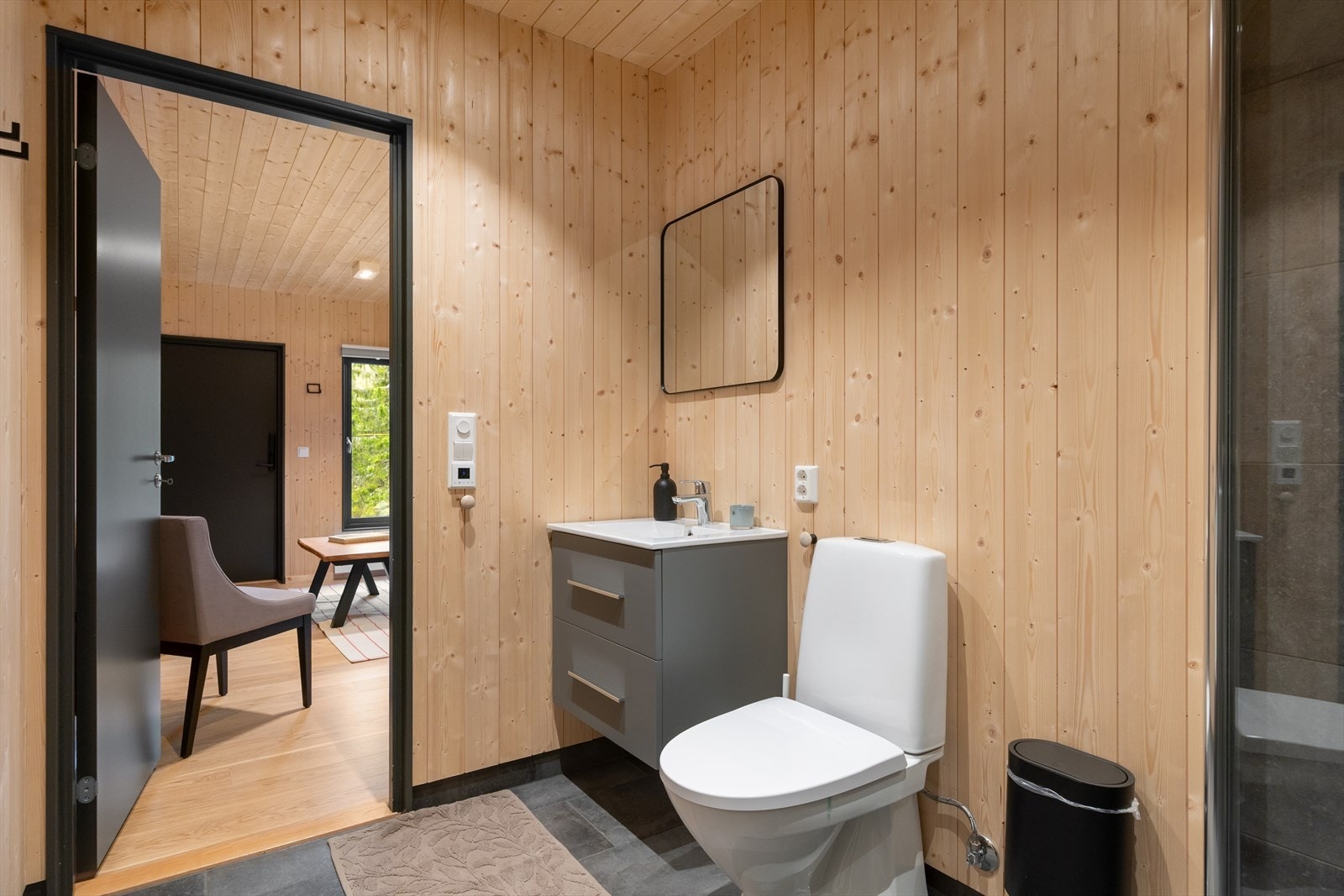 Rommet er utstyrt med gulvstående toalett, dusjhjørne med vegg og dør i herdet glass, servant med underskap, speil og belysning. Galleribilde