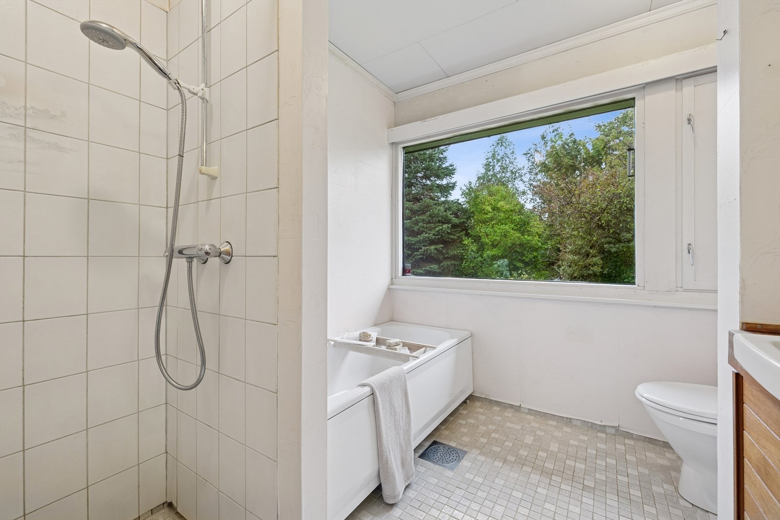 Badet er utstyrt med baderomsinnredning og dobbel servant nedfelt i benkeplate, underskap med dører, gulvmontert toalett, dusjhjørne, samt badekar. Galleribilde