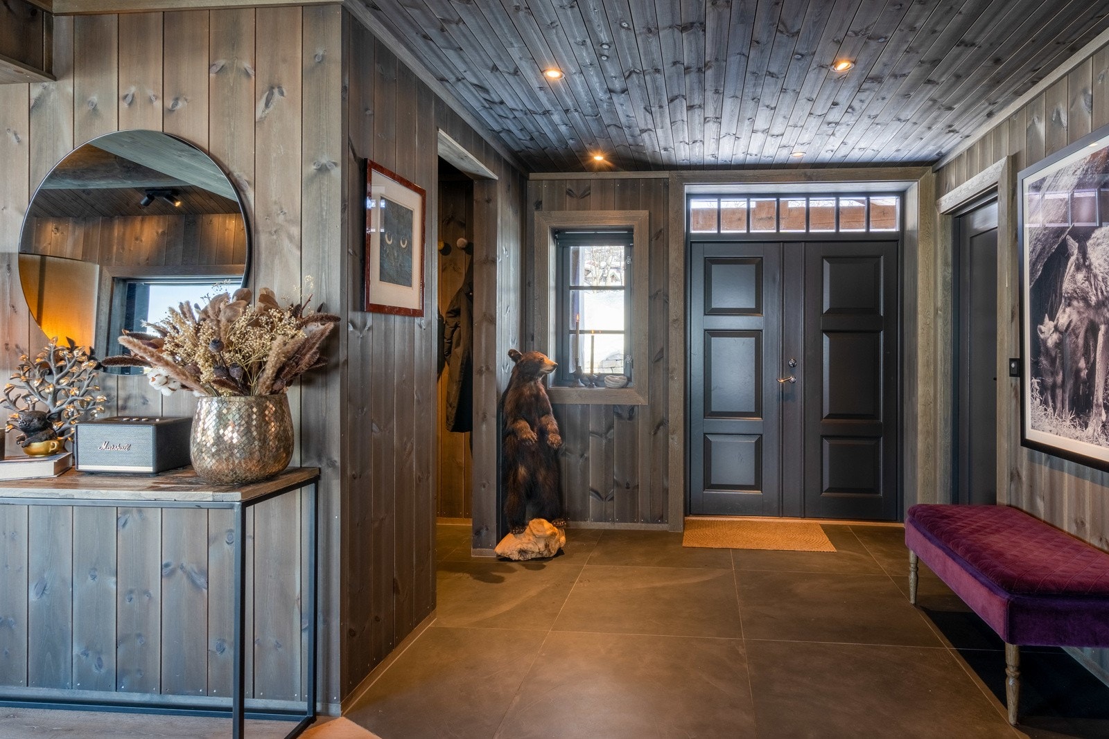 Velkommen inn - via en elegant tofløyet inngangsdør møter man en innbydende entré. Ytterklær og sko kan enkelt henges av i delvis åpen garderobe.