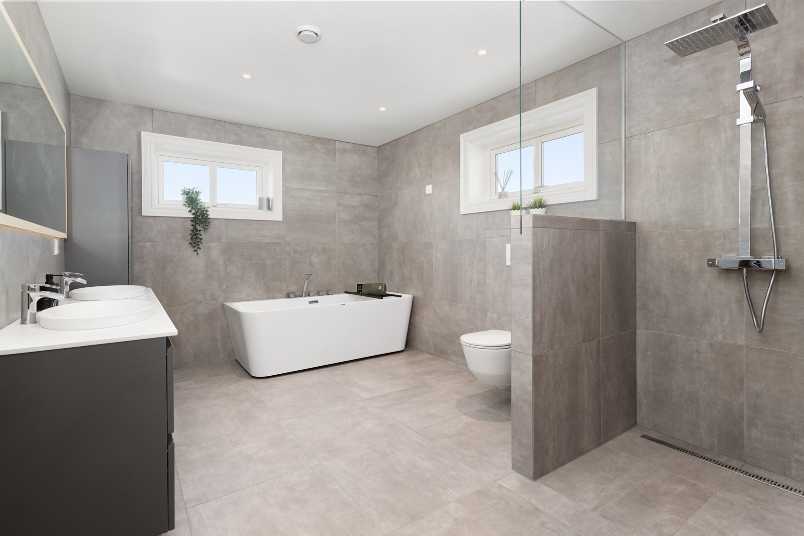 Rommet er av god størrelse og er innredet med gode oppbevaringsmuligheter i baderomsinnredning med to nedfelte servanter og i høyskap. Videre har rommet et badekar, dusjnisje og et veggehengt toalett. Galleribilde