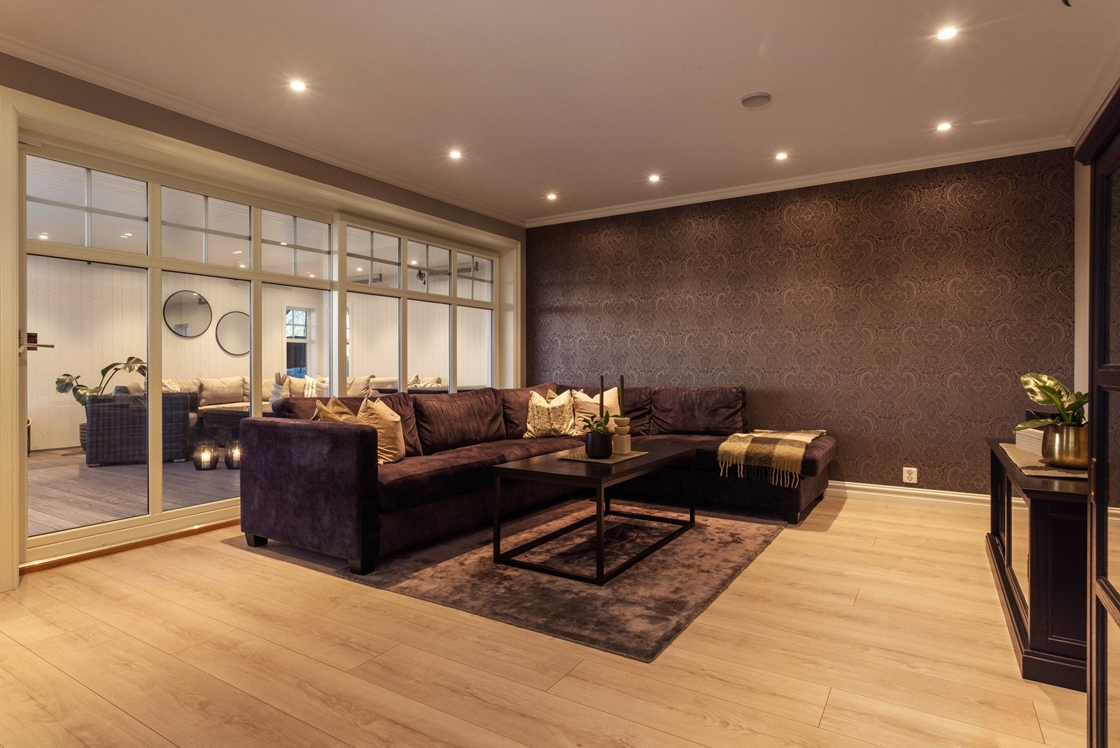 Store skyvedører fører videre ut til en overbygget uteplass og boligens terrasse. Galleribilde