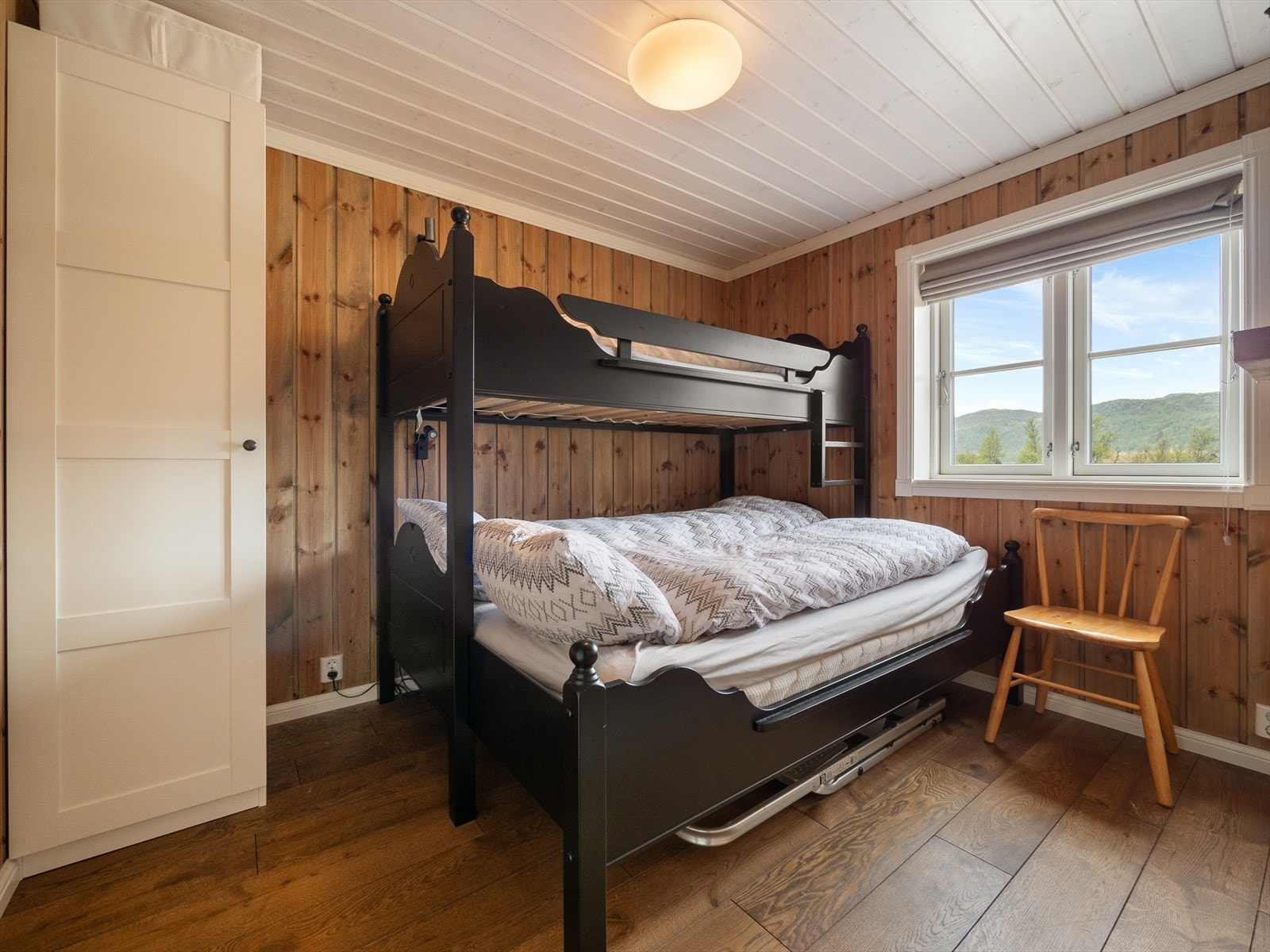 Hyttas andre soverom i hovedetasjen er også romslig og innredet med familiekøye. Det er godt med plass til garderobeløsning og annet møblement - et praktisk rom for både barn og gjester. Galleribilde