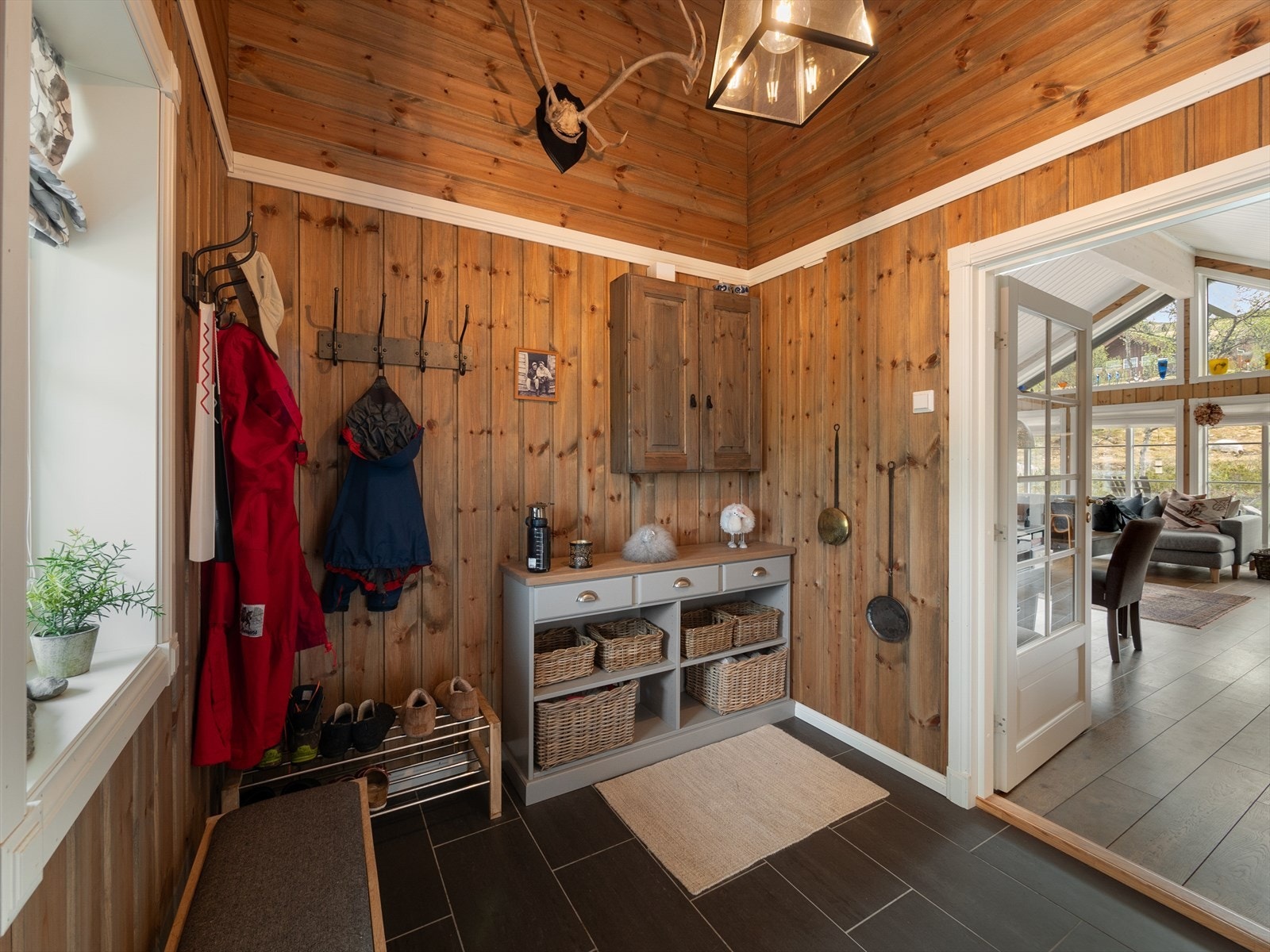 Romslig entré med fliser på gulv hvor det er tilhørende utvendig bod og vaskerom rett ved inngang. Galleribilde