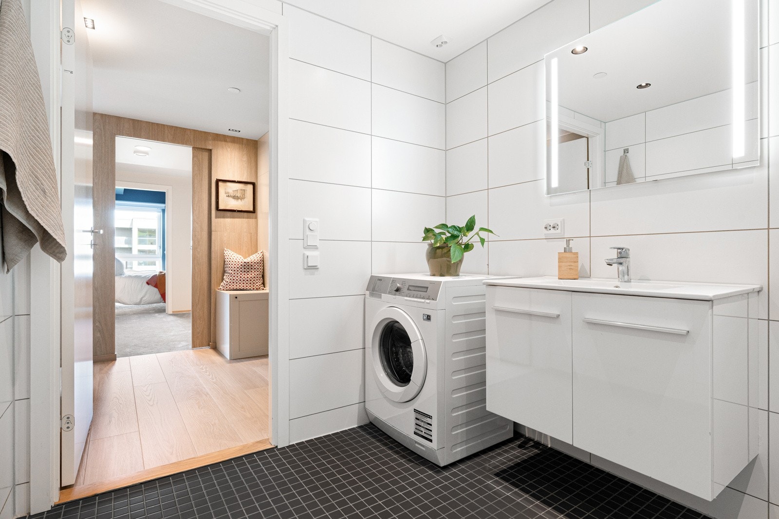 Leiligheten har et flislagt bad med nedfelt servant i stilren innredning, vegghengt toalett og opplegg for vaskemaskin. Galleribilde