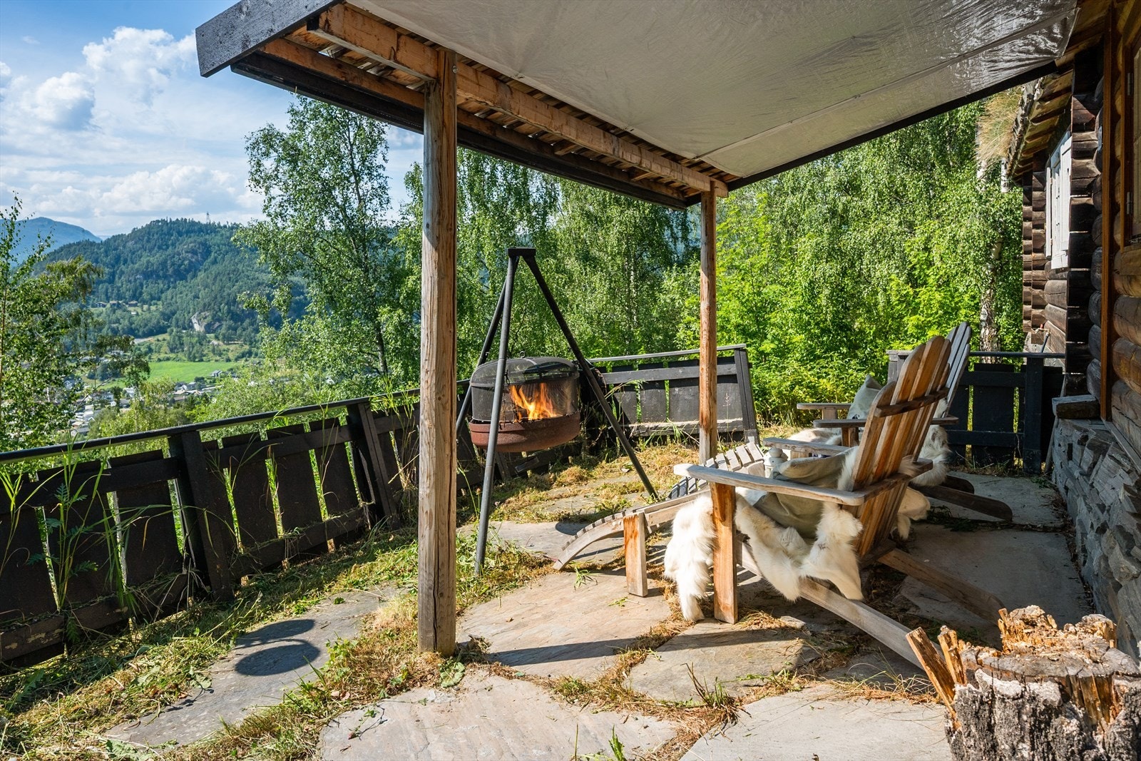 Plassen utenfor hytta har takoverbygg og det er lagt skiferheller på bakken. Galleribilde
