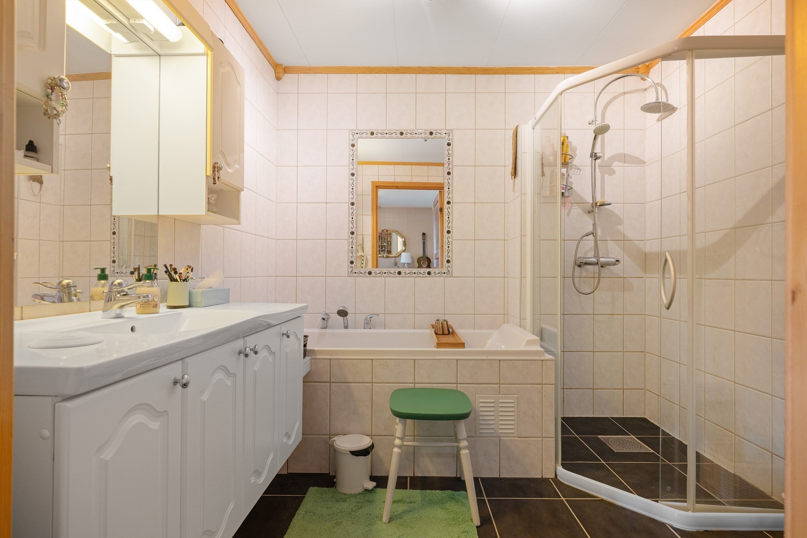 Pent flislagt bad på 6 kvm med gulvvarme og servantskap med overskap og speil med lys, vegghengt toalett, dusjhjørne med regndusj samt badekar. Galleribilde