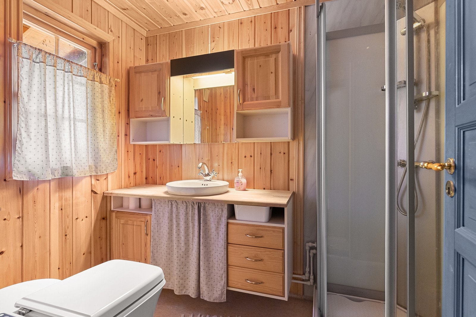 Bad med forbrenningstoalett. Det er vann til vegg. Vann fra pumpe til vask og dusjkabinett, med gråvann til terreng. Galleribilde