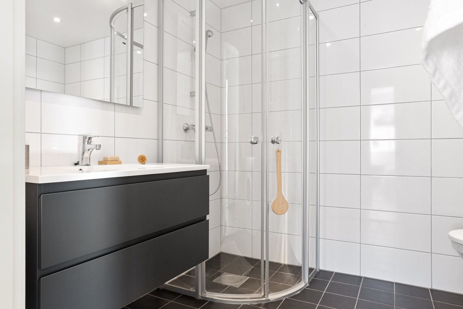 Badet er innredet med vegghengt toalett, servantmøbel med skuffer og dusj med glassvegger. Galleribilde