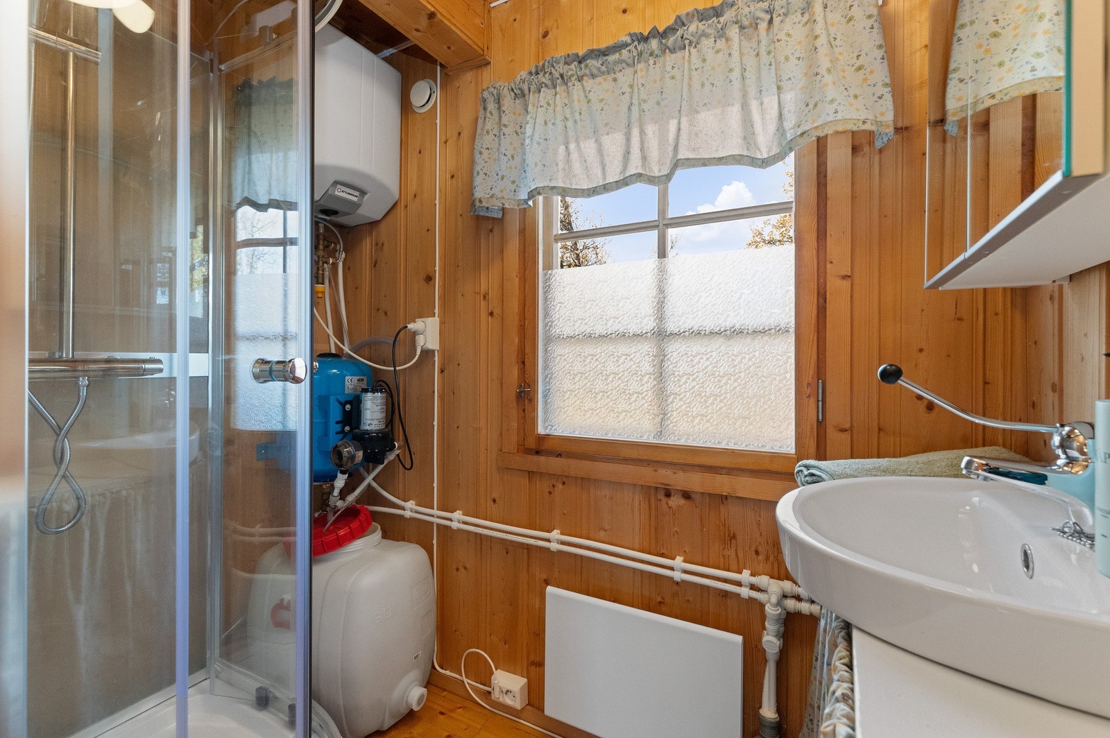 Badet har dusjkabinett, vask og speilskap. Det er cisterne/beholder som kan fylles med vann, elektrisk pumpe forsyner dusj og blandebatteri på vask. Dette er ikke en godkjent løsning, les i salgsoppgave for detaljer Galleribilde