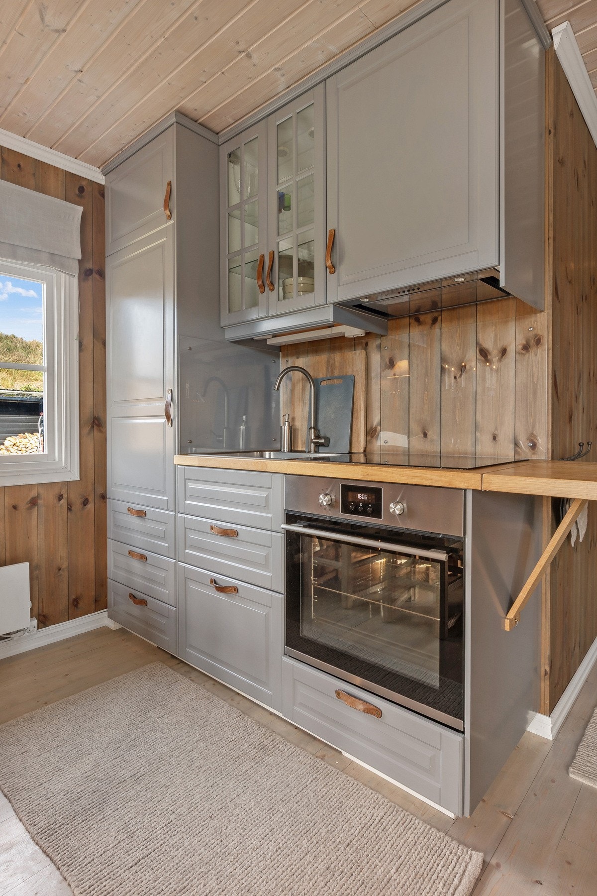 Lyst og praktisk kjøkken med innredning som består av laminerte skrog, profilerte fronter og benkeplate i laminat med nedfelt kjøkkenkum. Galleribilde