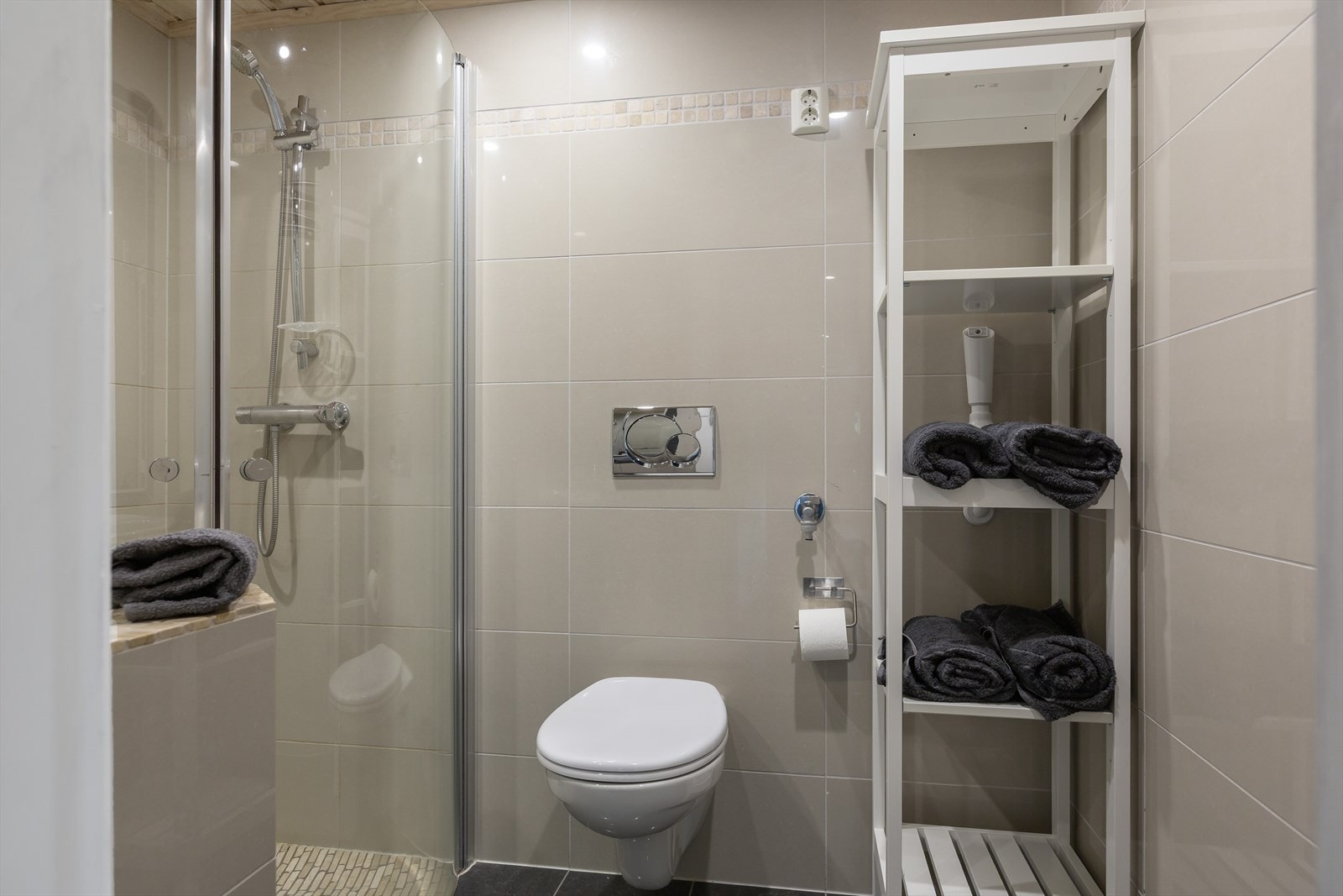 Bad 1 er innredet med dusjhjørne, veggmontert toalett og nedfelt servant. Galleribilde